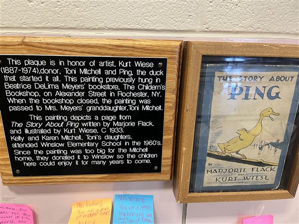 Close up of the plaque next to the painting and the Ping book